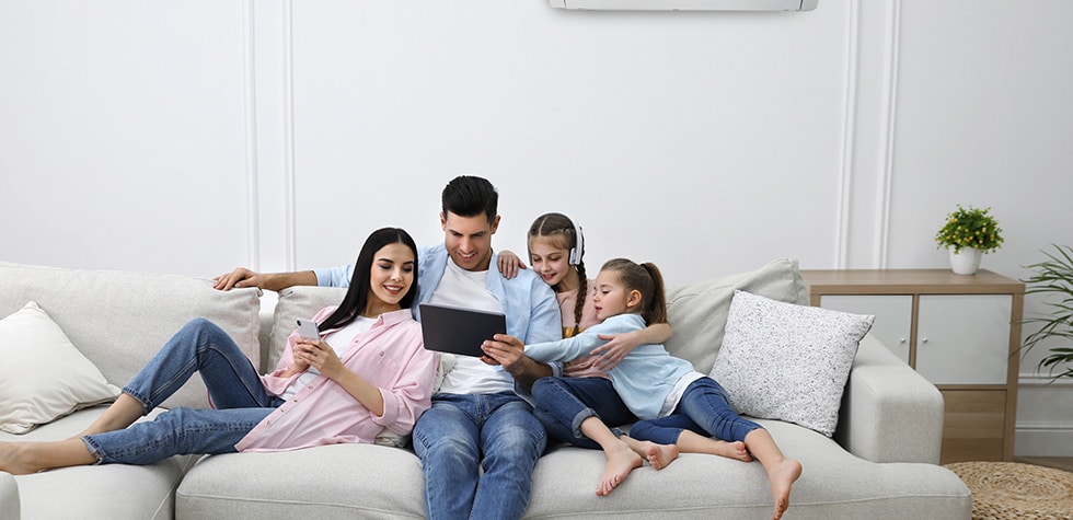 Happy family resting under air conditioner on white wall at home